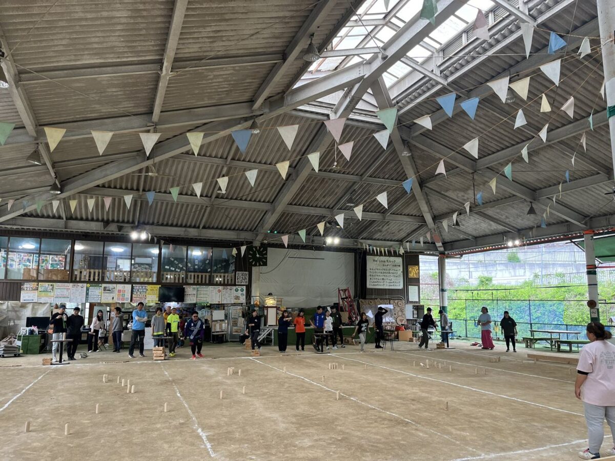 A large roofed Mölkky ground with bunting under the roof, several games in progress
